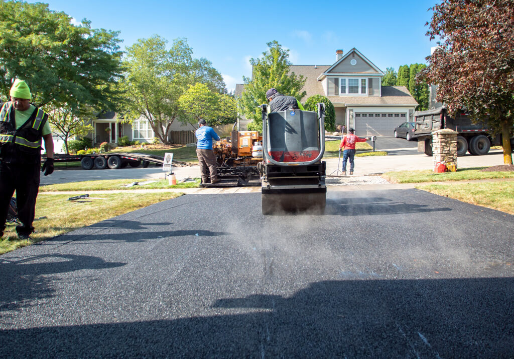 Roller compacting a freshly paved residential driveway