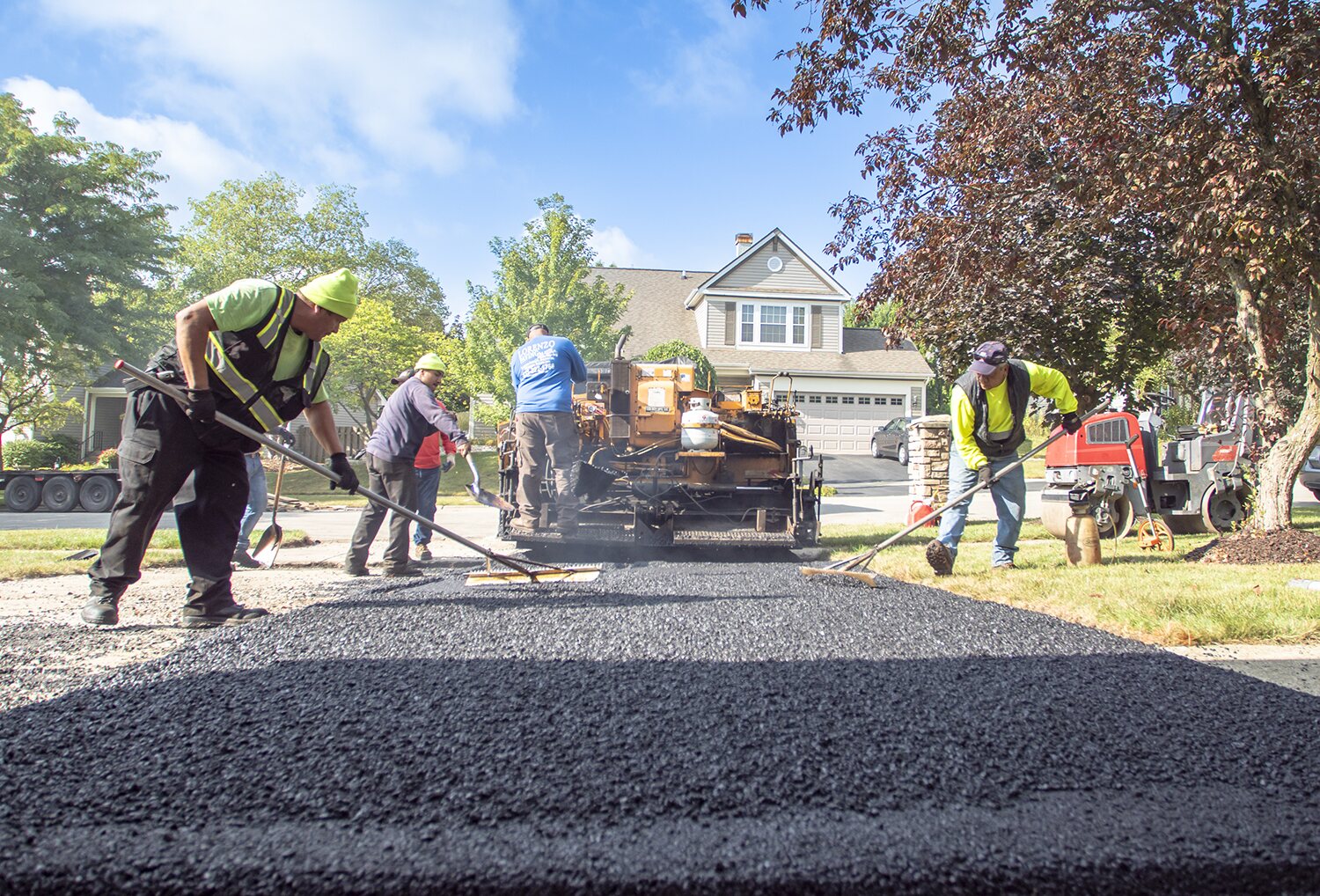 Paving crew laying fresh asphalt on a residential driveway